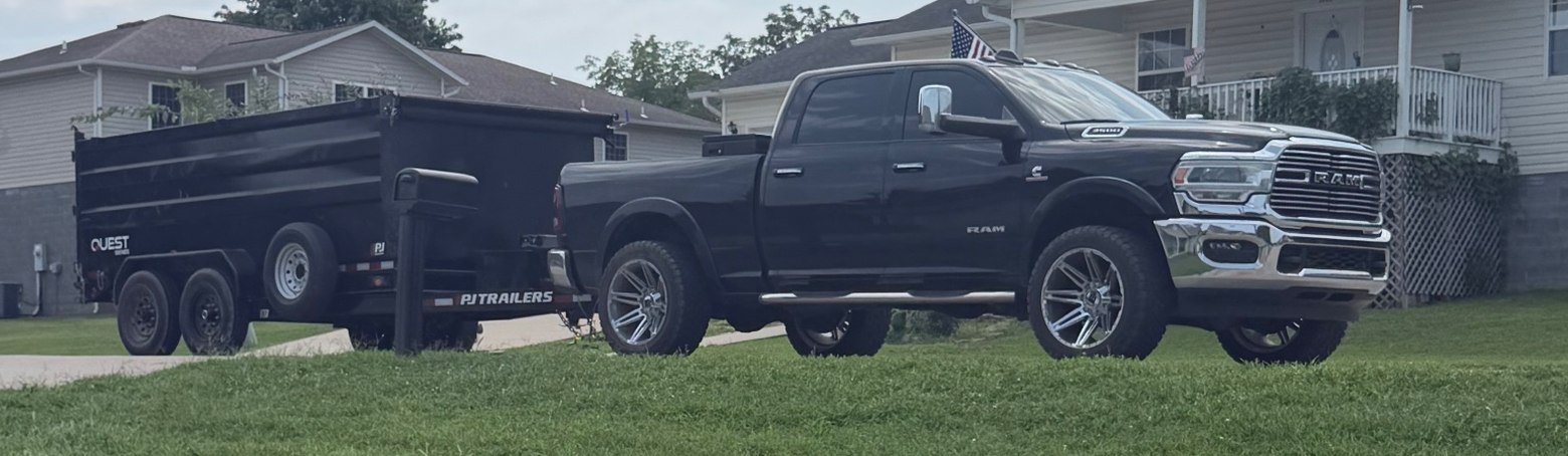 Pickup and dump trailer standing on a cut lawn before loading